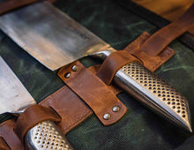Close-up of chef knife handle secured with leather strap in waxed canvas knife roll