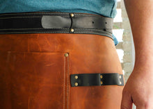 Detail shot of a custom leather apron with a black leather belt and sturdy brass studs, perfect for restaurant workers and professionals who prefer a durable, personalized apron for daily wear.