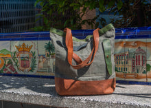 Eco-friendly canvas and leather tote bag with green and brown tones, photographed on a bench with traditional Spanish tiles in the background