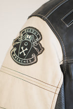 Close-up of Dugout Wrenches patch on white leather sleeve of biker jacket