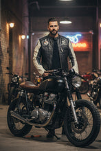 Man wearing black and white café racer leather jacket standing next to vintage motorcycle