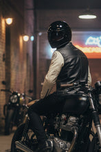 Rider in black helmet and black and white café racer leather jacket on motorcycle front view
