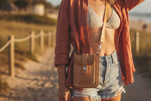 Woman wearing yellow leather crossbody bag by Fashion Racing on the beach at sunset