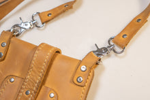 Close-up of adjustable strap and metal clasp on yellow handcrafted leather bag.
