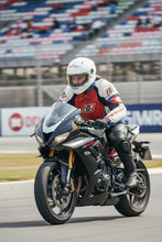 Man riding a sport motorcycle wearing red white and blue leather racing jacket