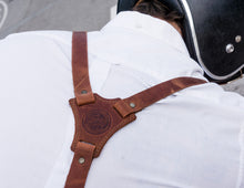 person wearing the brown leather suspenders. The suspender straps intersect at a leather patch on the back, which is embossed with the brand's logo and text that appears to say "Fashion Racing Handmade Custom Leather"