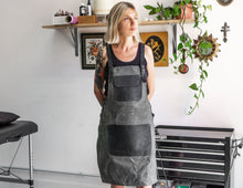 grey canvas apron with black leather pockets and straps