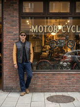 A man wearing a motorcycle black leather jacket with tan sleeves 