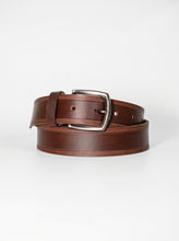 A brown leather belt with a silver-tone metal buckle, neatly coiled on a light gray background.