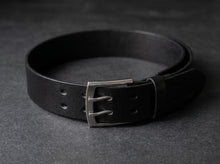 Black full-grain leather belt with brushed silver buckle and rounded tip.
