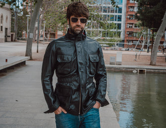 A front view of a black leather jacket for men, featuring a sleek design with zippered pockets and a stand-up collar.