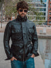 A front view of a black leather jacket for men, featuring a sleek design with zippered pockets and a stand-up collar.