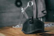 Black leather motorcycle shifter protector with white stitching for footwear protection.
