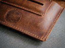 Handmade brown leather tobacco pouch with stitched edges and built-in rolling paper holder