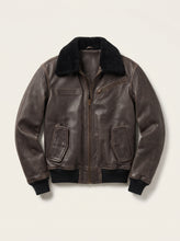 A dark brown leather aviator jacket with a black shearling-style collar, black ribbed knit cuffs and hem, and a front zipper, shown on a light beige background.
