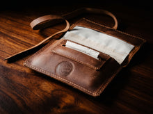 Handmade brown leather tobacco pouch with rolling paper holder and long leather strap.