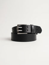 A black leather belt with a silver-tone metal buckle, neatly coiled on a light gray studio background.