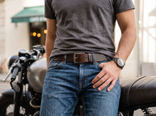 A man wearing a dark brown leather belt with a silver buckle