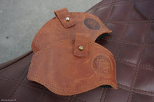 Brown leather motorcycle shifter protectors with stitched edges for shoe protection.
