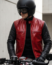 Person wearing a red black leather riding jacket and black helmet on a motorcycle.