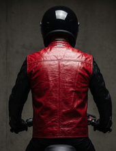 Person wearing a red black leather jacket on a motorcycle against a dark background