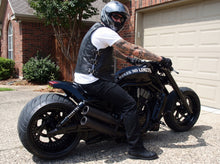 Black leather motorcycle vest with adjustable side buckles worn by a biker on a custom motorcycle