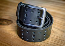Black perforated leather belt rolled with oversized silver buckle for detailed product view
