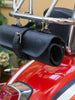 Black leather motorcycle tool roll securely fastened to the back of a red motorcycle Vespa. The handcrafted leather roll bag features a buckle closure and is neatly attached to the chrome frame behind the seat, ready for transport of tools