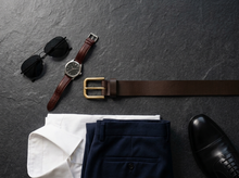 Brown full-grain leather belt with antique brass buckle styled for classic menswear