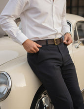 Brown full-grain leather belt with gold-tone buckle worn with navy trousers