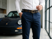Brown full-grain leather belt with gold-tone buckle worn with navy trousers