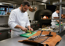 Professional chef using brown leather knife roll bag by Fashion Racing in restaurant kitchenProfessional chef using brown leather knife roll bag by Fashion Racing in restaurant kitchen. 