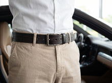 Dark brown crocodile-pattern leather belt with silver buckle worn with beige trousers