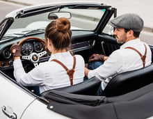 man and women wearing leather suspenders, vintage fashion outfit in convertible car with scenic view