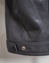 Close-up of a dark gray leather vest with a button on a neutral background