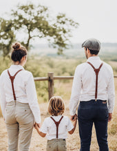 Family - man, women, child of three with matching brown leather suspenders, outdoor field setting, classic style