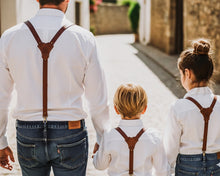 Man, woman and child wearing brown leather suspenders, vintage family outfit