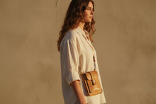 Side profile of woman wearing small yellow leather crossbody bag in natural light. 