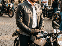 Men’s grey leather cafe racer jacket worn while riding a classic motorcycle
