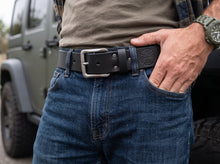 Man wearing a black genuine leather belt with a matte silver buckle, paired with blue jeans and a casual shirt. Premium men's leather belt for everyday wear, work, and outdoor style.