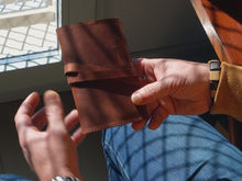 Video - Vintage leather tobacco pouch with wrap closure. Handmade travel-friendly rolling accessory for smokers. Compact and durable design, ideal for storing rolling papers, filters, and tobacco on the go