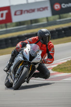 Motorcyclist wearing Fashion Racing red leather jacket leaning into a turn on a sportbike