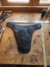 Black full-grain leather gardener tool holster displayed on a workbench with measuring tape, leathercraft tools, and thread spools, highlighting its handmade craftsmanship and size. Durable gardening utility belt with tool loops and front storage pocket for pruning shears, secateurs, trowels, florist tools, and essential garden equipment. Perfect for gardeners, florists, landscapers, horticulturists, greenhouse workers, and personalized gifts.