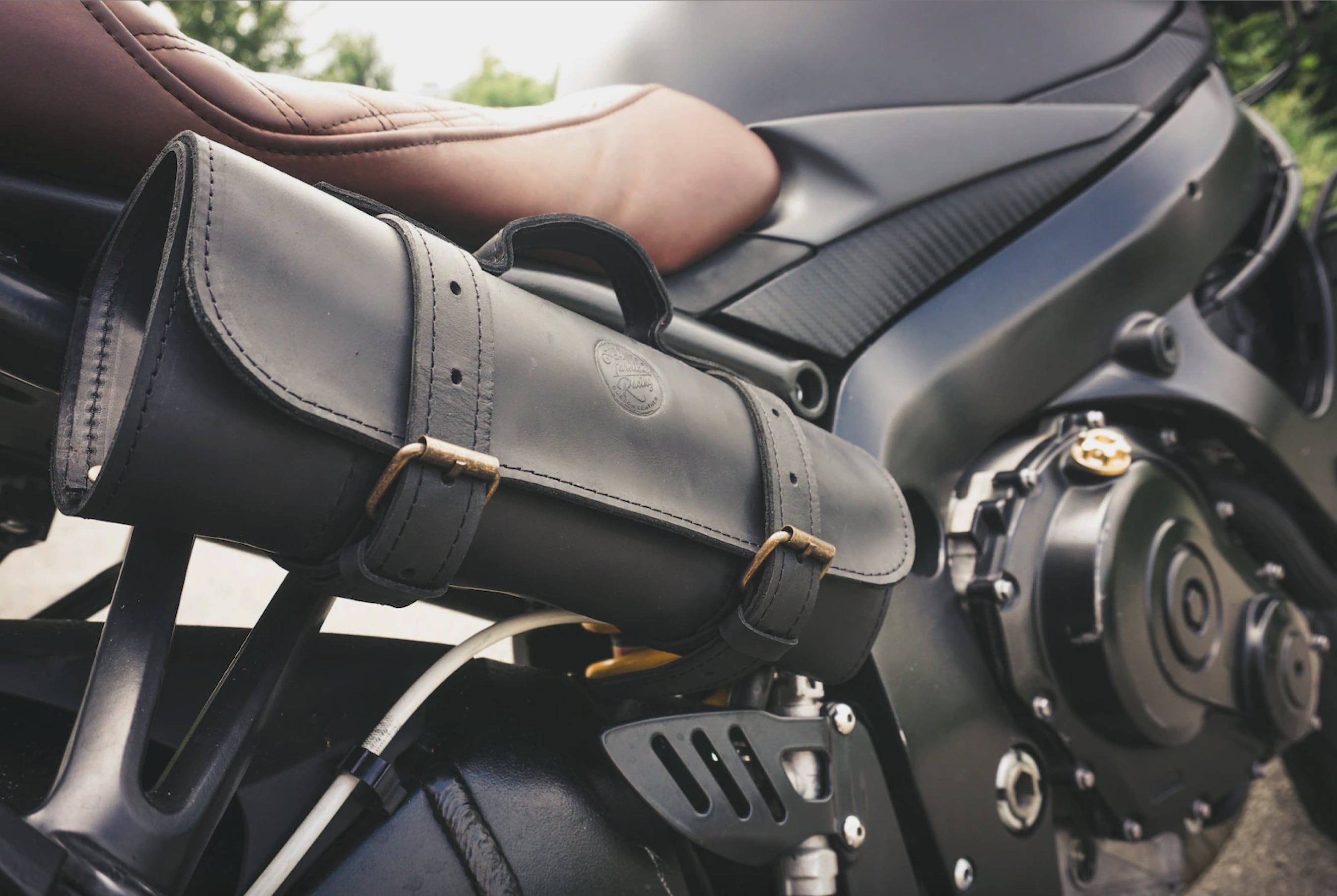 A close-up of a leather tool roll unrolled, revealing a neatly arranged set of tools for motorcycle maintenance.